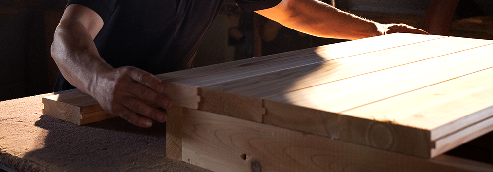 A craftsman assembling high-quality cedar sauna panels, showcasing the wood’s natural beauty and durability for premium outdoor saunas