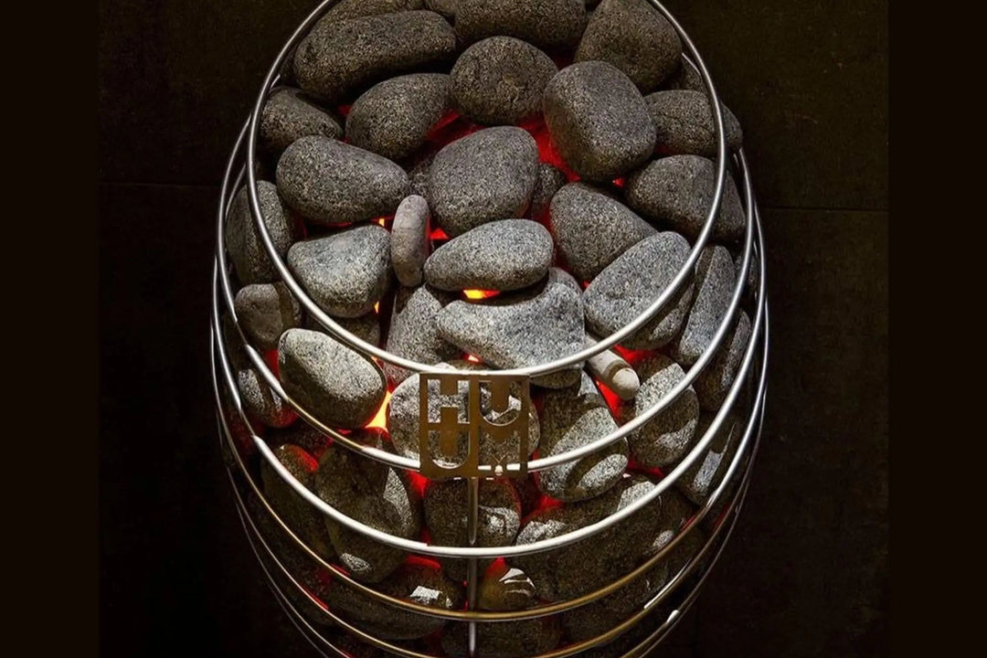 HUUM Drop electric sauna heater glowing behind a ring of sauna stones