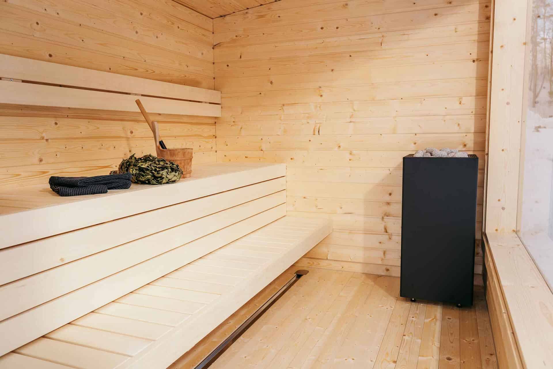Wooden sauna interior with a black radiator and benches.