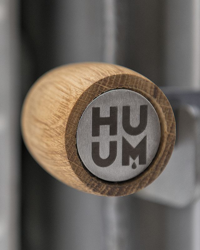 Wooden handle with 'HUUM' branding on a metallic background
