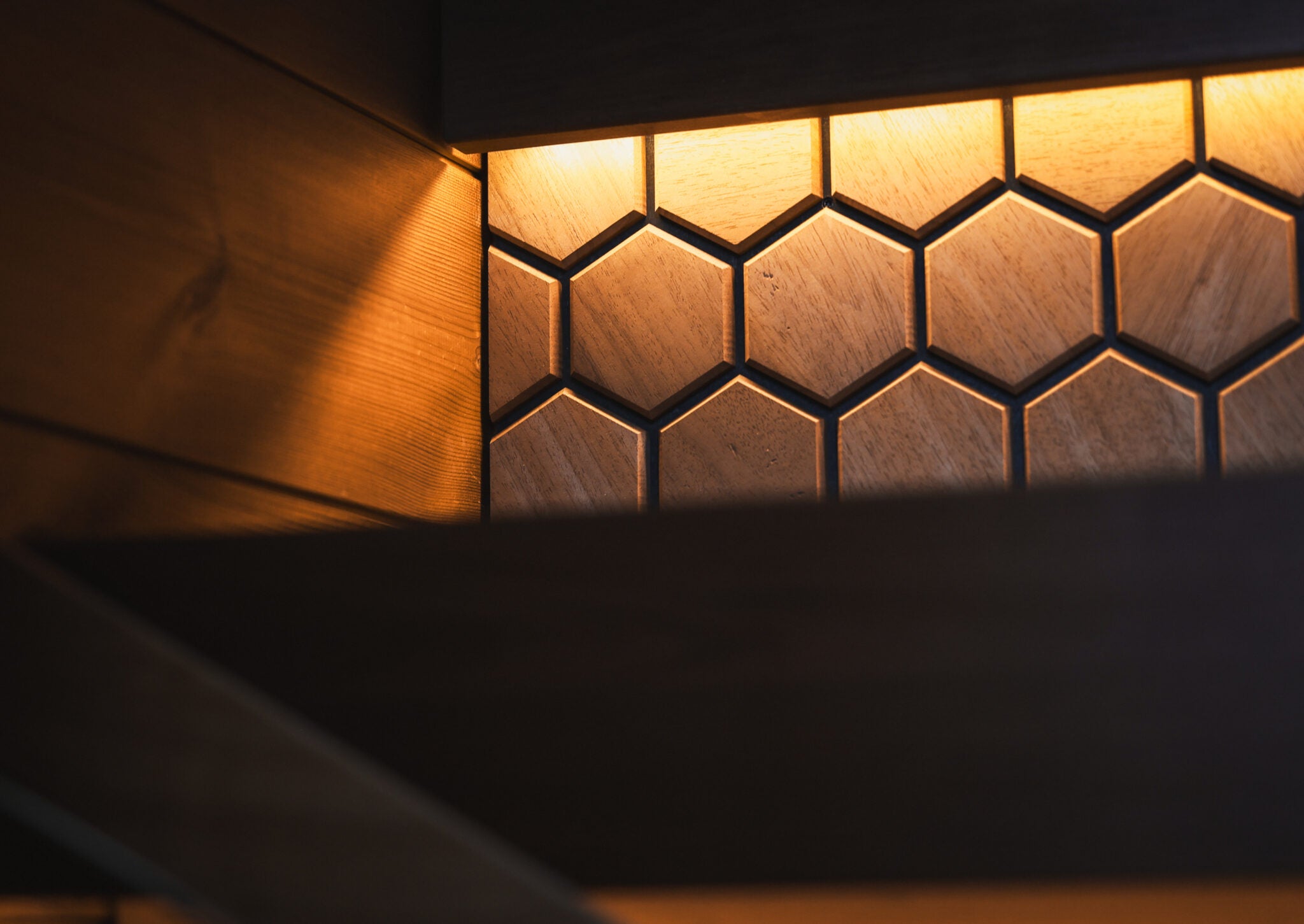 Hexagonal light fixture casting a warm glow on a dark background