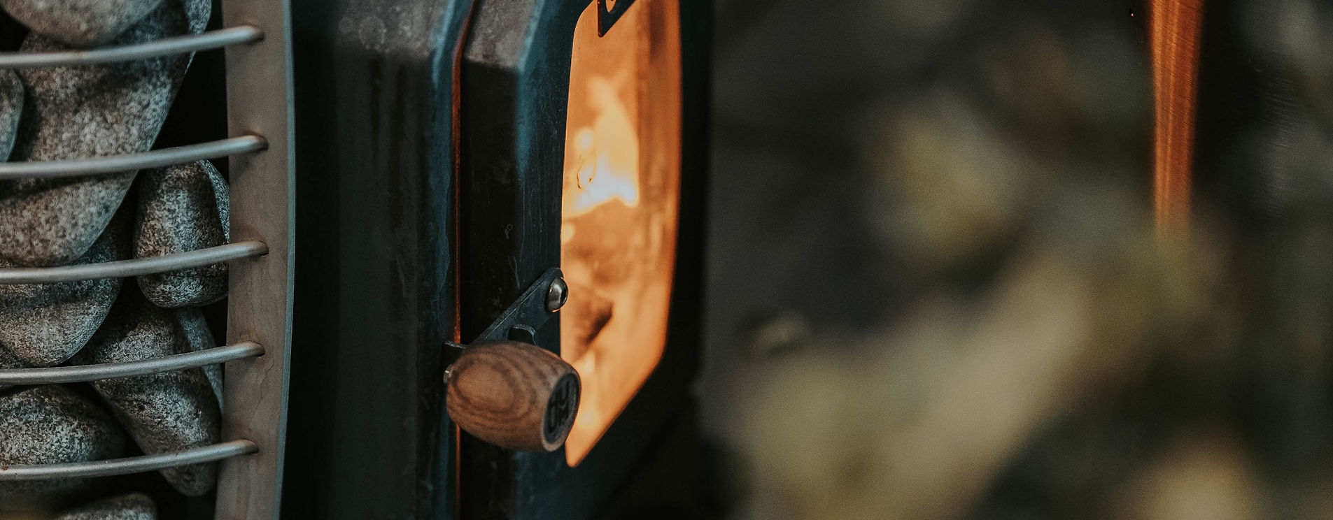 Close-up of a person wearing a dark coat with a hood, standing in front of a blurred background.